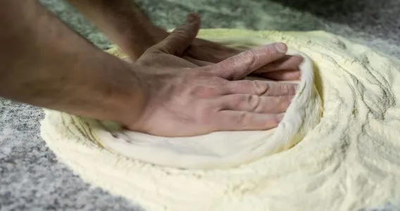pizzaiolo stende l'impasto della pizza